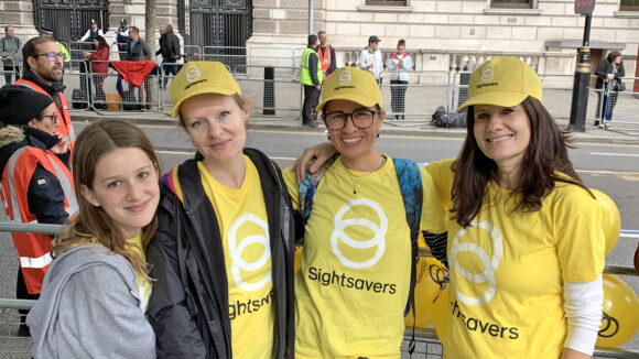 A group of smiling women wearing Sightsavers t-shirts and caps.