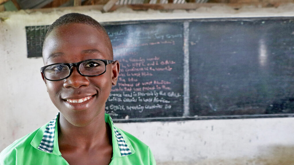 Arthur in the classroom, smiling while wearing his new glasses.