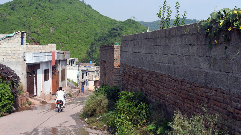 A man on a motorbike travelling through rural Pakistan.