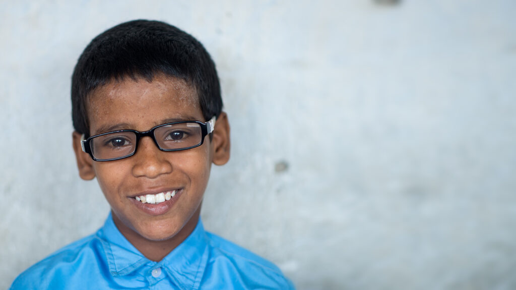 A young Shahid smiles while wearing his new glasses.