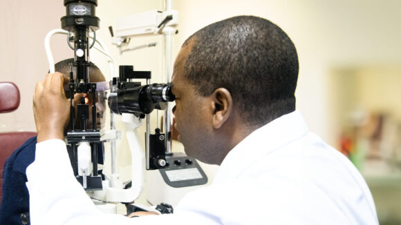 A doctor uses equipment to check the eyes of a young boy.