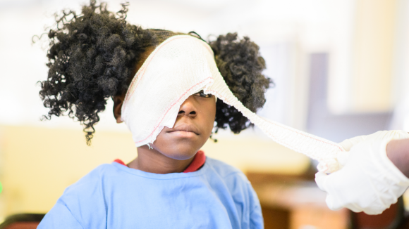 A young cataract patient has her bandage removed.