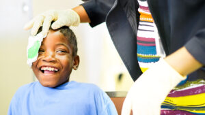 A young girl smiles broadly as her bandage is removed following cataract surgery.