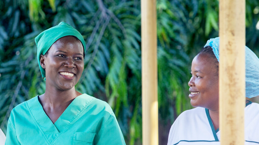 Dr Gladys walks with a female health worker, all wearing medical scrubs.