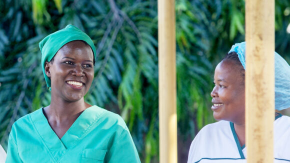 Dr Gladys walks with a female health worker, all wearing medical scrubs.