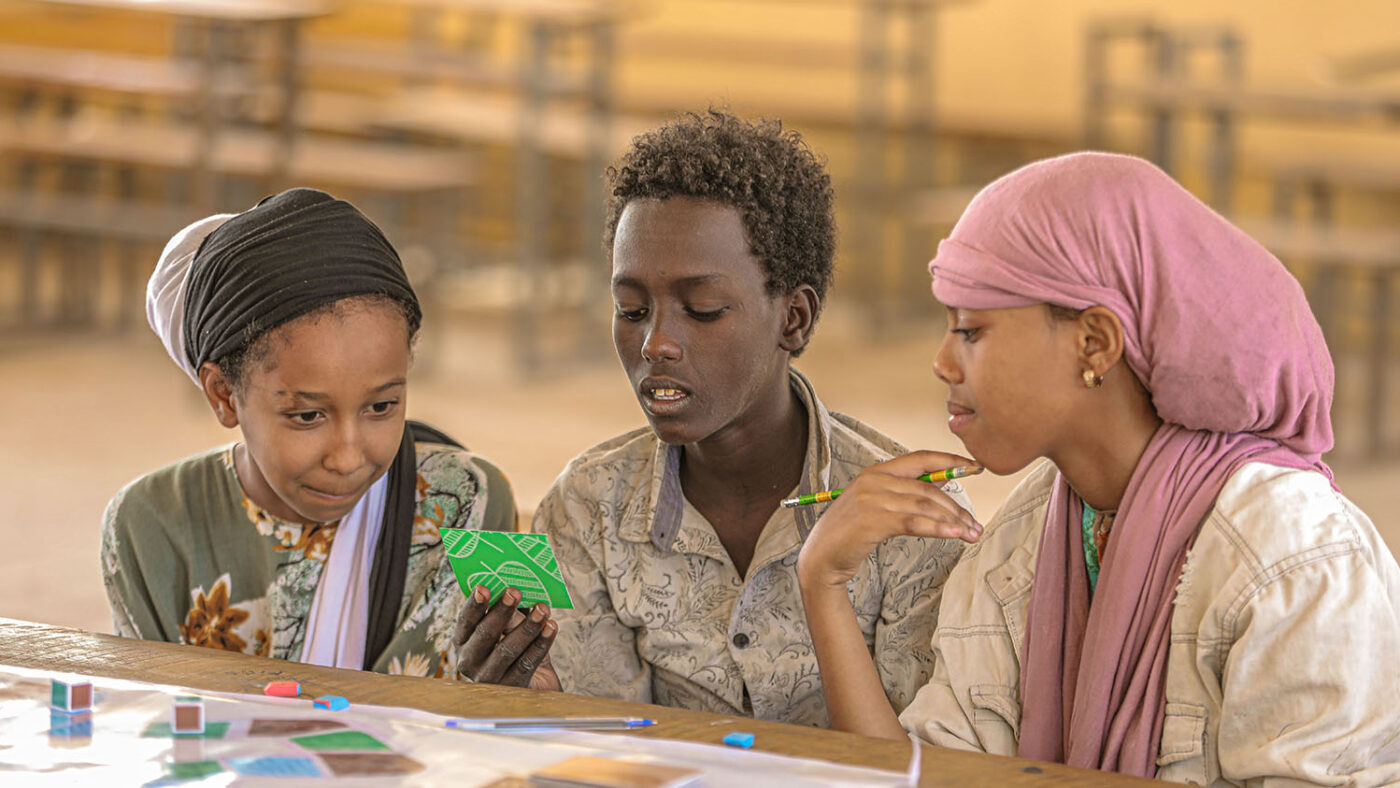 Three students in Ethiopia play a board game that teaches them about hygiene and trachoma.