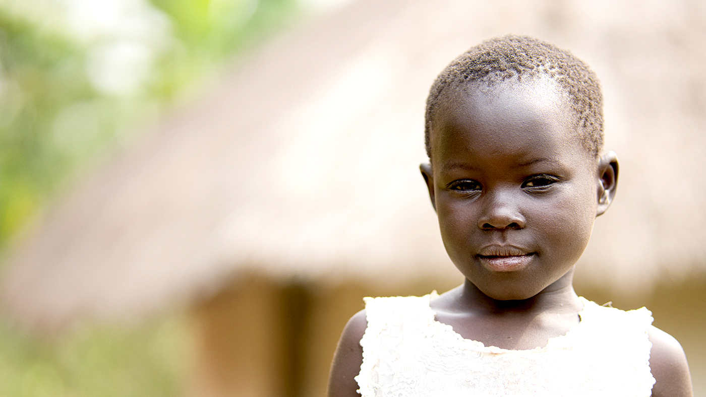 Six-year-old Happy smiles outside her home in Uganda.