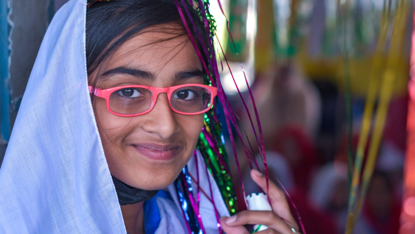 Aakasha, a young girl, smiling in her doorway.