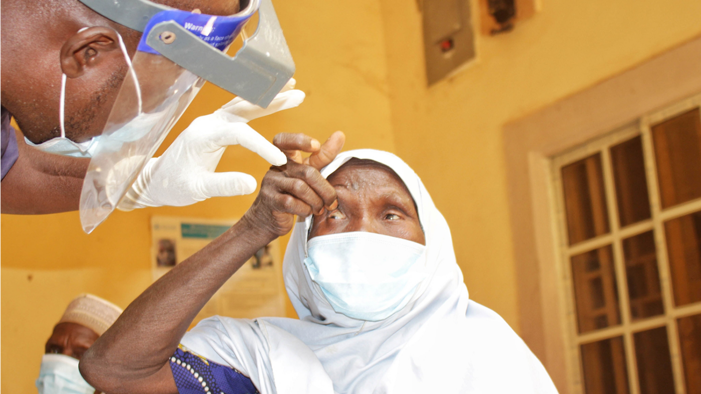 A surgeon inspects a trachoma patient's eyes.
