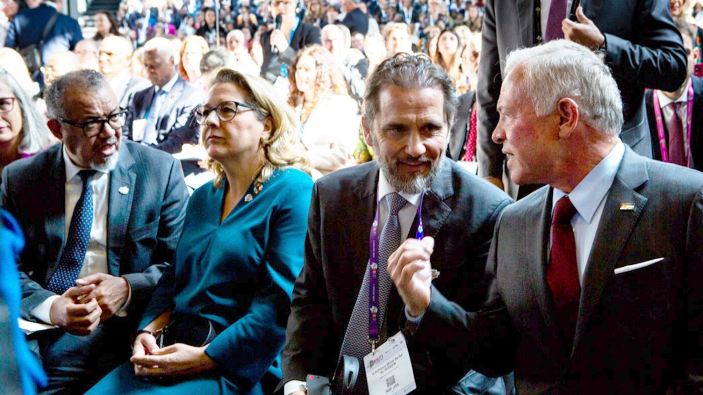 A huge room full of people, with four smartly dressed attendees in the foreground.