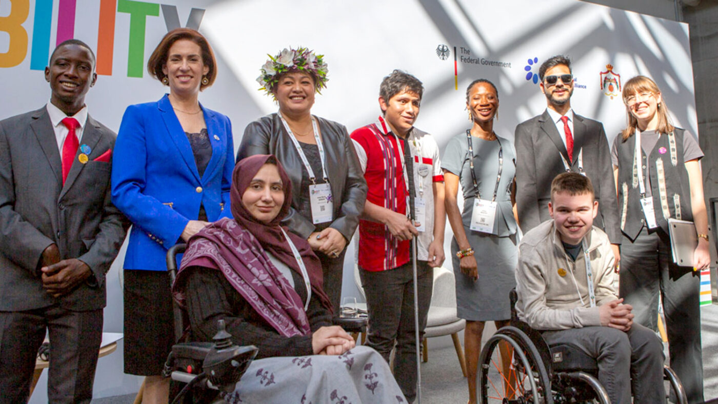 A group of people smiling at the conference, some with disabilities.