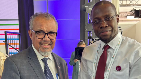 Two men dressed in shirts and ties smile at the camera.