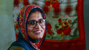 Aasiya wearing a pair of glasses. She has a colourful scarf over her hair.