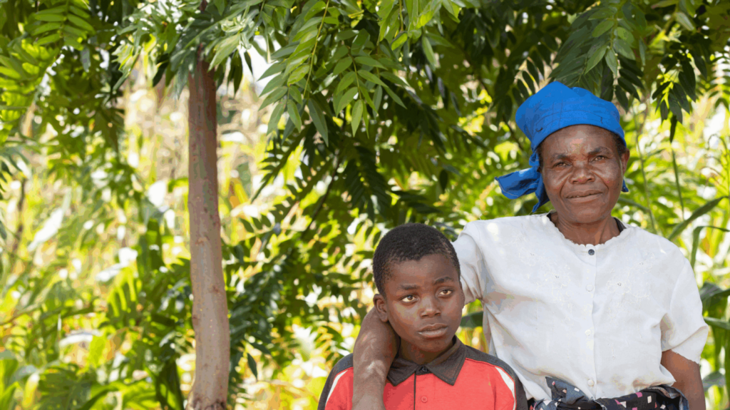 A woman smiles as she puts her arm around a young boy.
