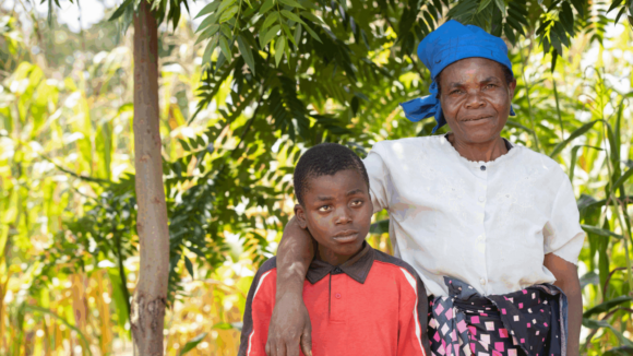 A woman smiles as she puts her arm around a young boy.