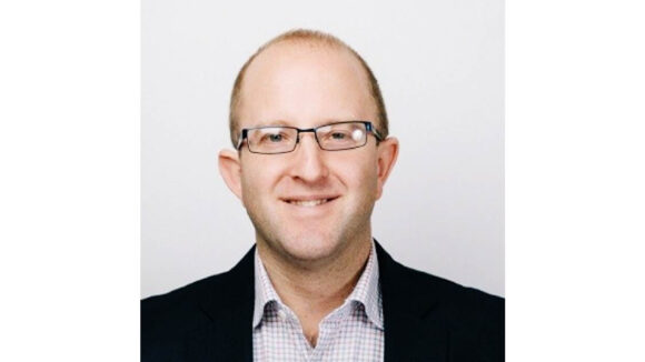 A man with glasses on smiles.