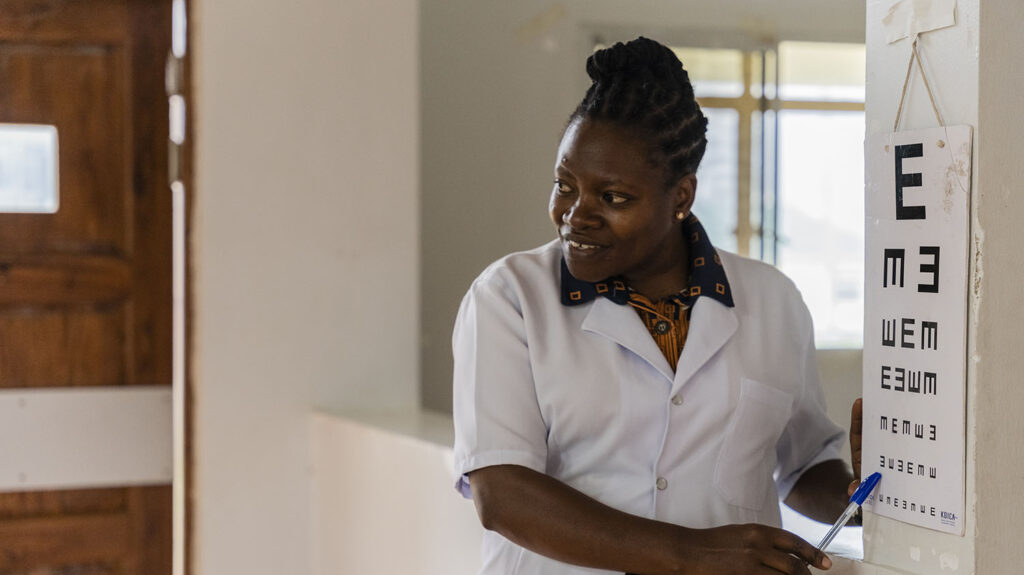 A female eye doctor points to a letter on a chart during an eye test.
