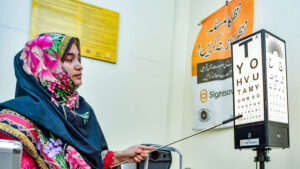 A female optometrist points to a row on a Snellen chart.