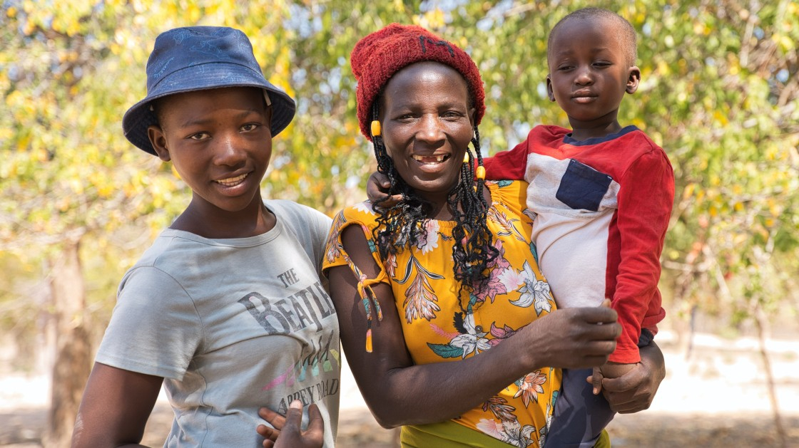 Maria holds a young child while standing next to a teenage girl.