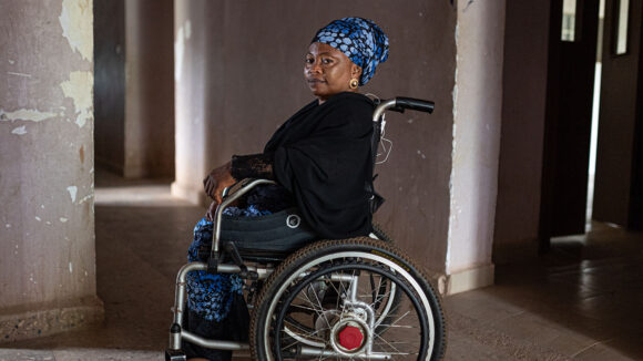 A woman wearing a head scarf sits in a wheelchair at a health centre.