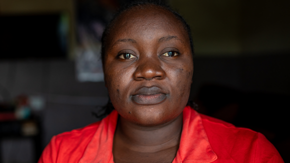 A woman stares into the camera with a neutral expression on her face.