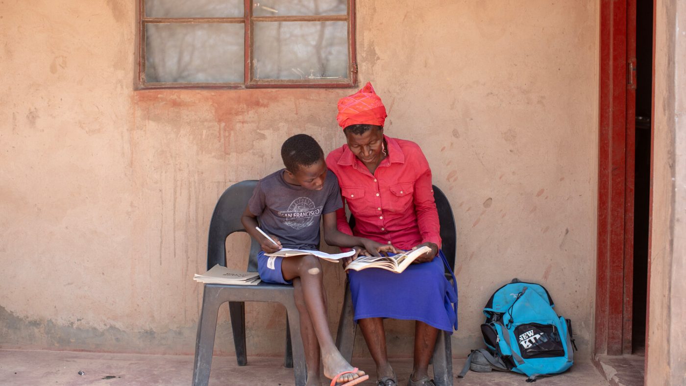 Twinde and his mother, Cecilia, sitting outside their home doing homework together.