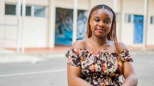 A young woman with braids outside a building in an urban area.