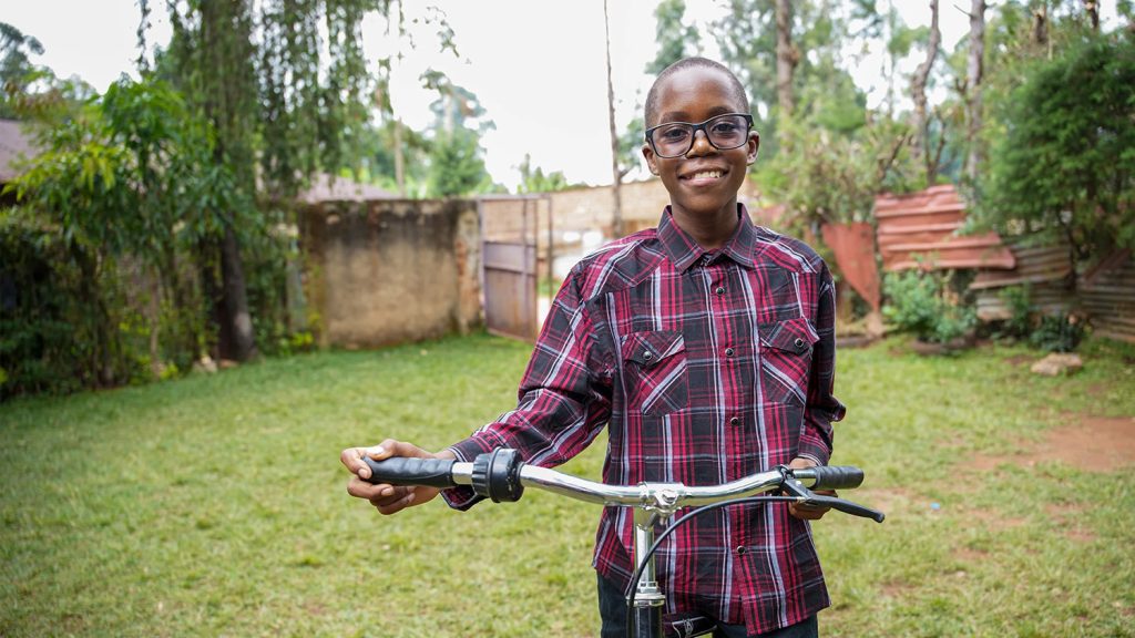 Jayden is wearing a pair of glasses and holding a bike.