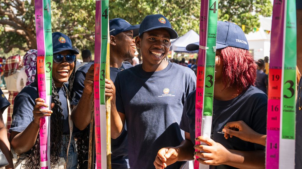 Volunteers, who are holding dose poles, gather before a community drug campaign.