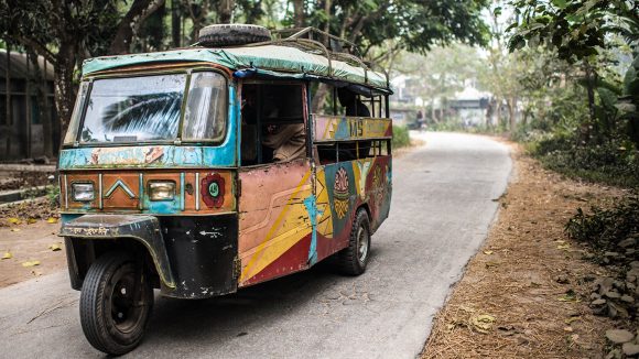 A tuk-tuk travels down a road in Bangladesh.